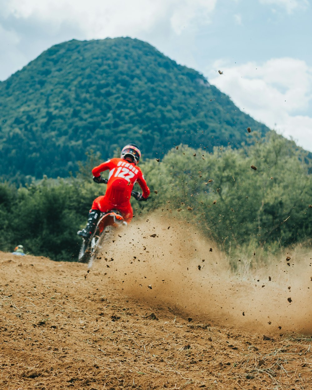 a person riding a bike on a dirt trail with trees in the background