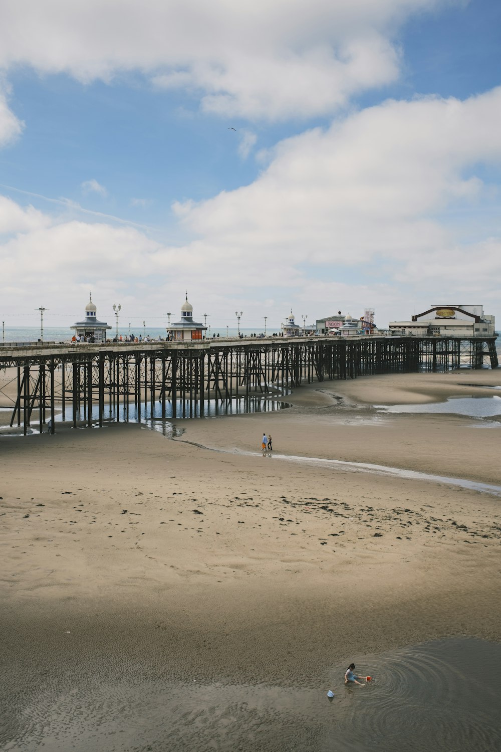 a pier with a beach and buildings in the background