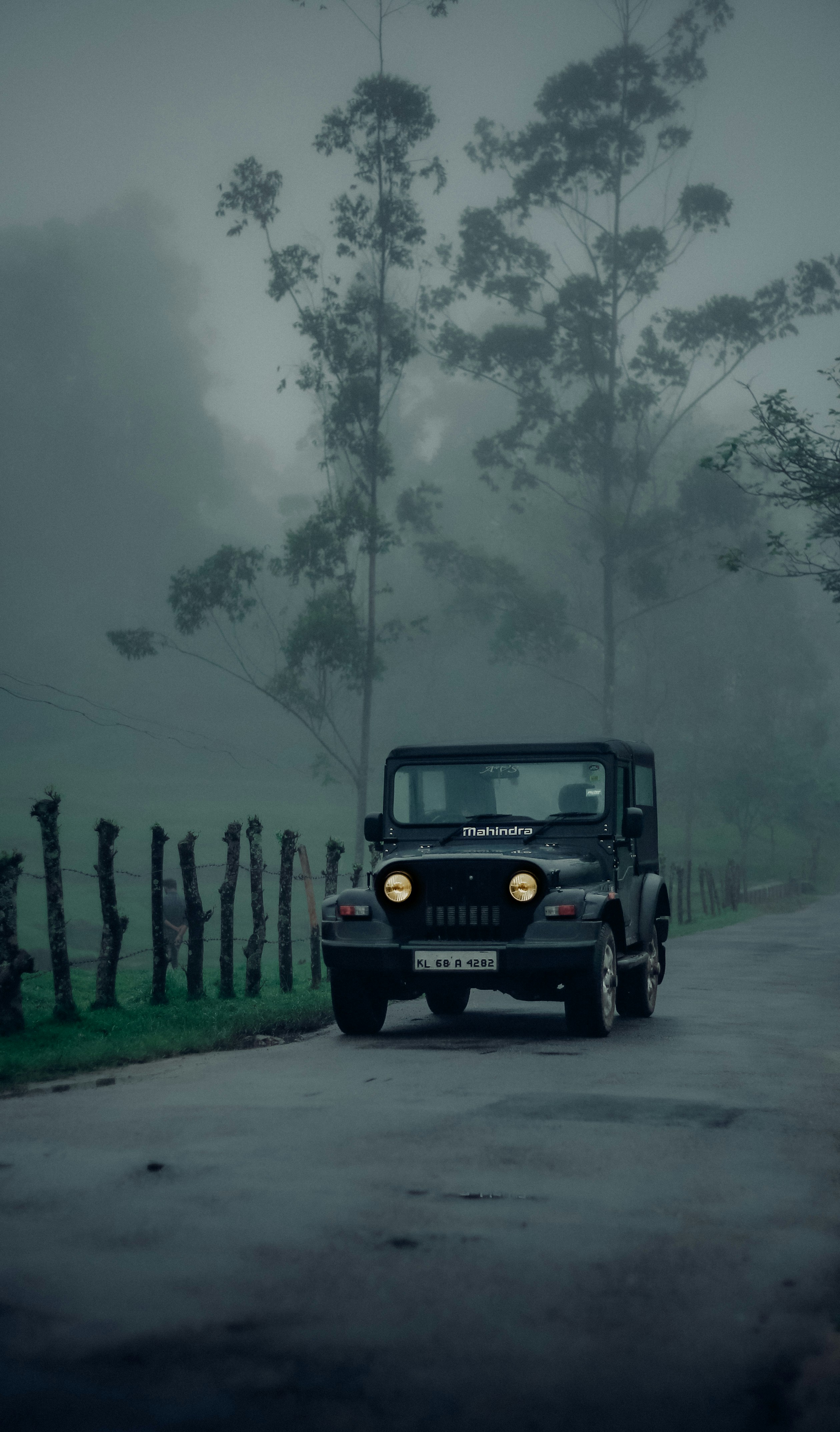 Mahindra Bolero SUV - dark green vehicle on mountain road with misty forested hills in background, ideal for Mullayanagiri tours