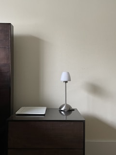 A minimalist wooden lamp on a bedside table, highlighting natural grain and soft ambient light.