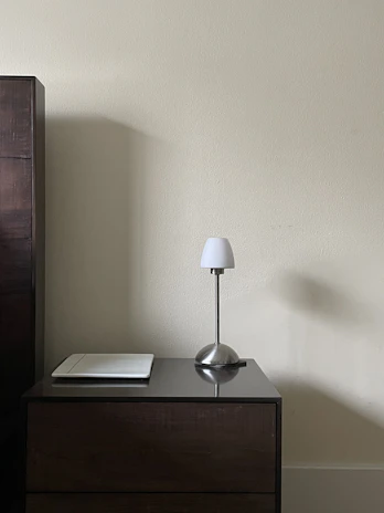 Minimalist bedside table featuring a delicate lamp and a small potted plant.