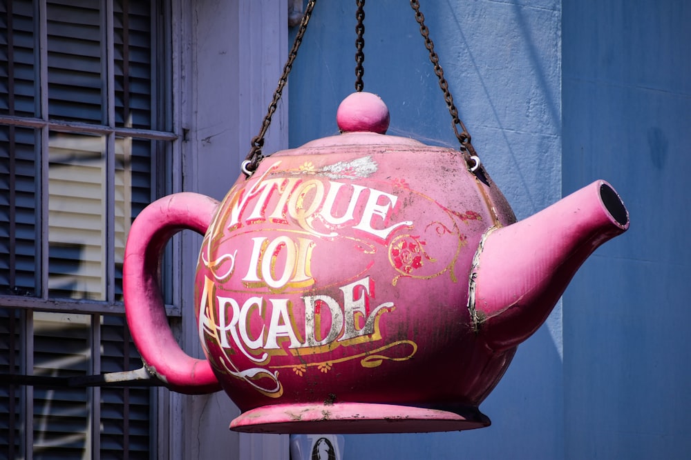a red teapot with a pink handle