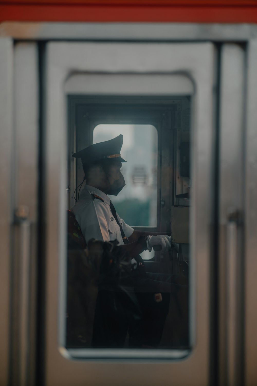 eine Person mit Hut und Mantel in einem Fenster