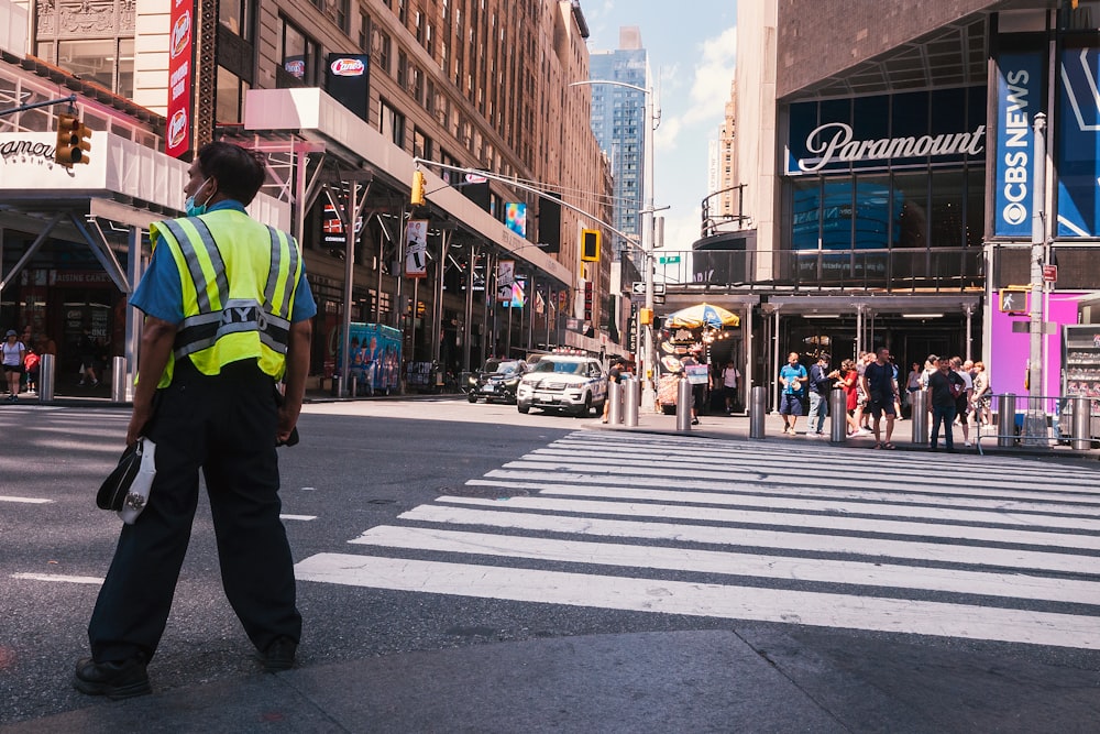 a person in a yellow vest standing in the middle of a street