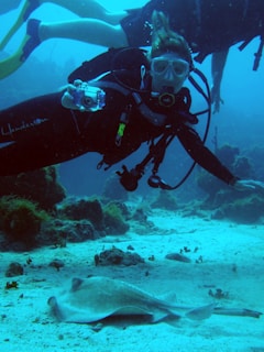 A diver documenting underwater marine debris with a waterproof camera near a rocky seabed.
