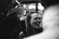 A candid black and white photo of a smiling person surrounded by family during a joyful gathering.