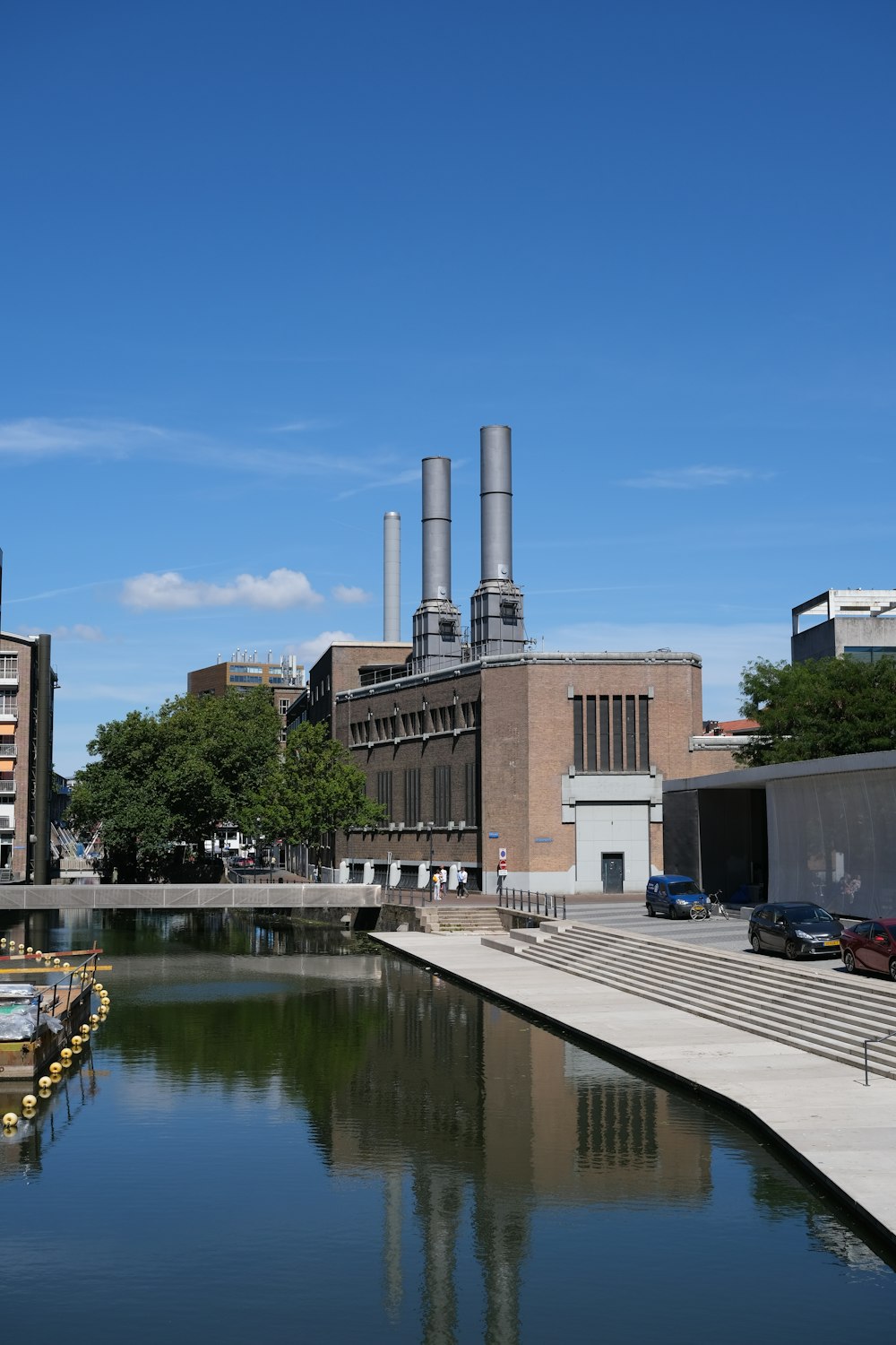 a building with smokestacks by a body of water
