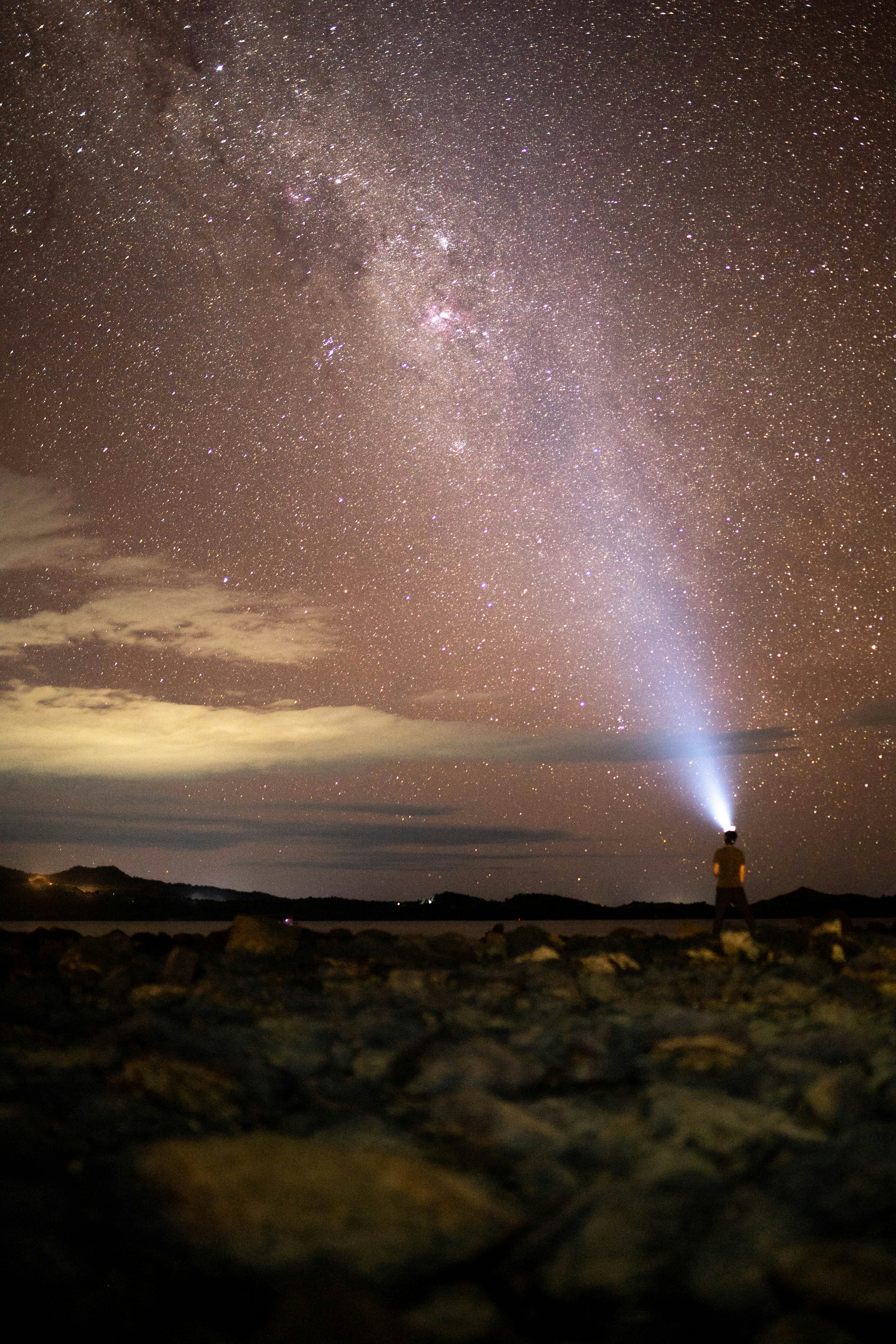 a person standing on a rocky hill with a bright light in the sky