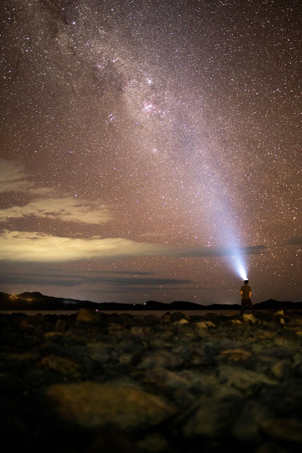 a person standing on a rocky hill with a bright light in the sky