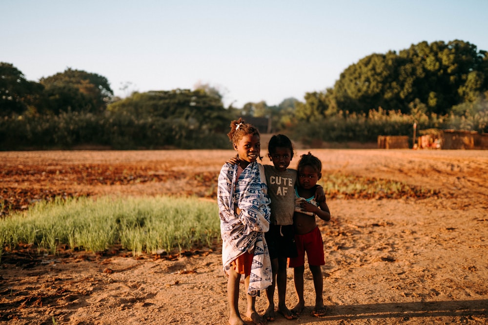 a group of children standing in a dirt field
