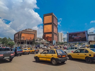 a group of cars parked in a parking lot with buildings in the background