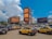 a group of cars parked in a parking lot with buildings in the background