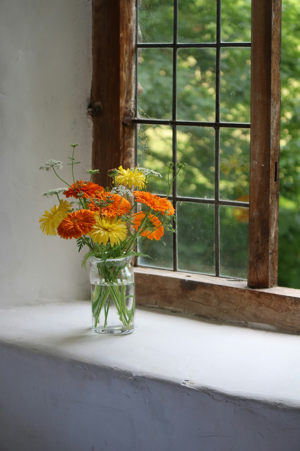 a vase of flowers sits on a window sill
