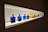 A row of colorful bottles with gold caps are displayed on a well-lit shelf. The bottles contain various vibrant liquids, ranging from deep blue to bright yellow, red, and green. The light from the shelf highlights the colors, creating a striking visual effect.