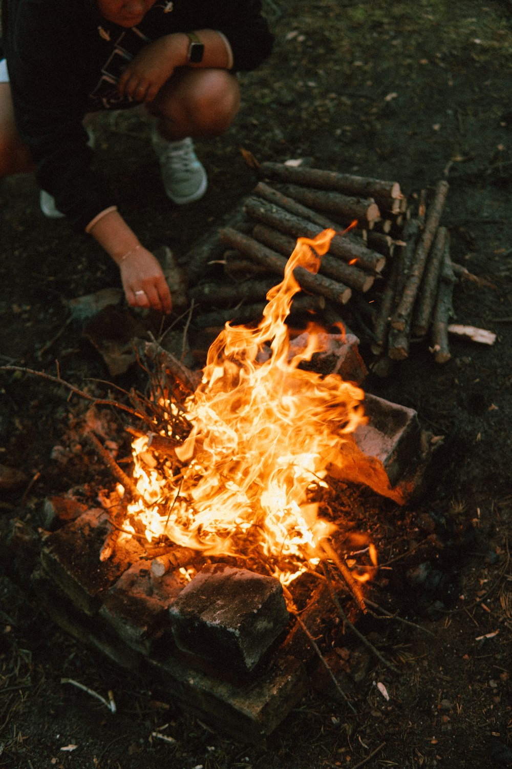 a person kneeling next to a fire