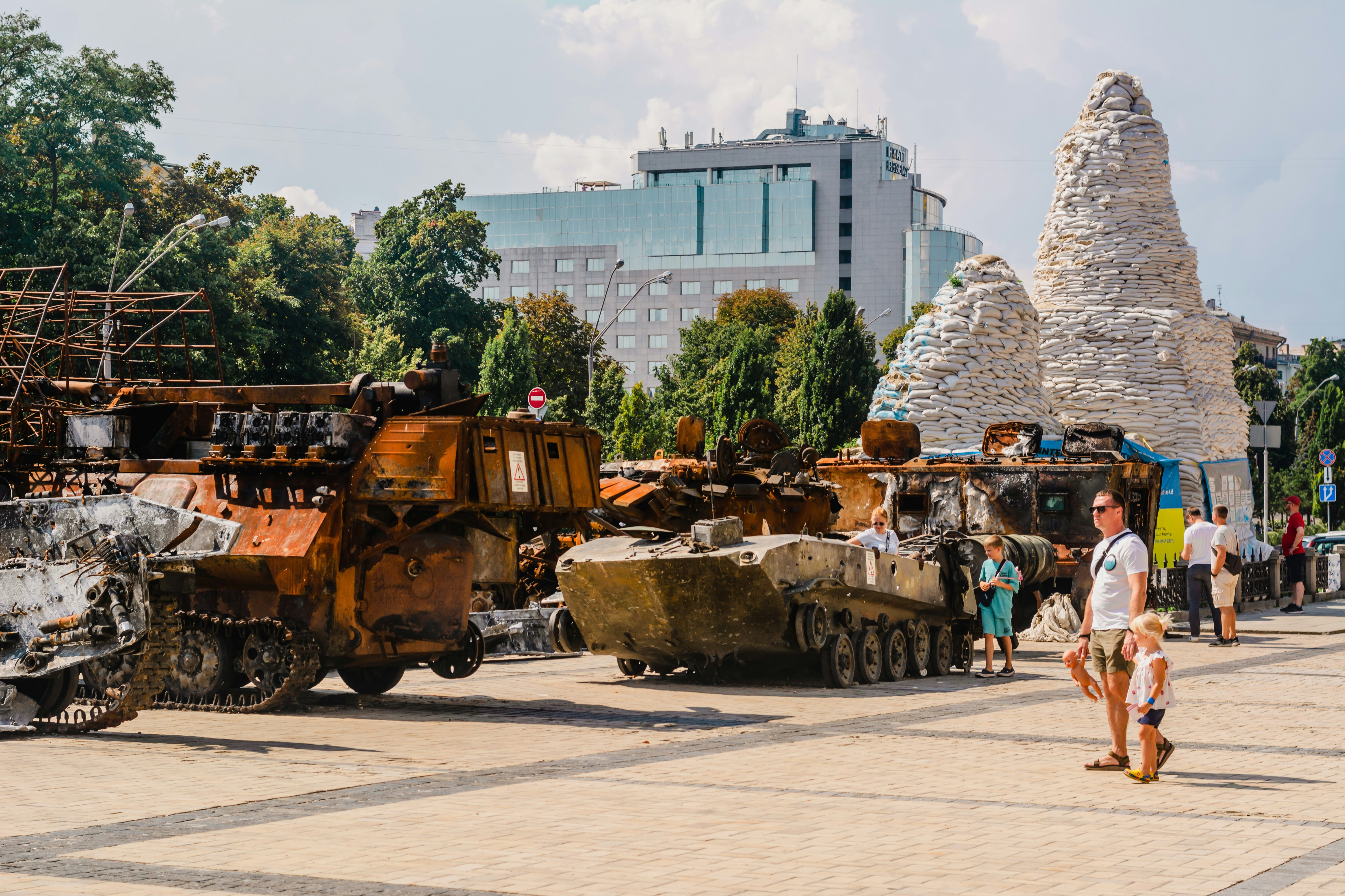 a group of people standing next to tanks on a street