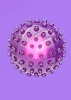 A spherical object resembling a virus or a molecular structure is depicted in a purple hue with protrusions evenly distributed across its surface. The center of the sphere emits a bright pink glow, adding a translucent effect to the sphere.