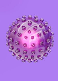 A spherical object resembling a virus or a molecular structure is depicted in a purple hue with protrusions evenly distributed across its surface. The center of the sphere emits a bright pink glow, adding a translucent effect to the sphere.