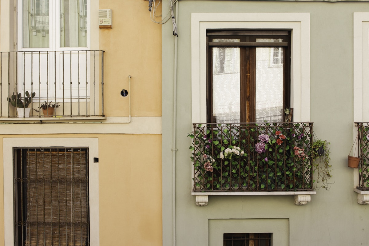 Colorful European apartment building facades with small flower-filled wrought-iron balconies