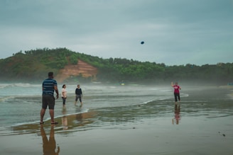 A group of casual disc golfers laughing and throwing discs through a sun-dappled forest clearing.