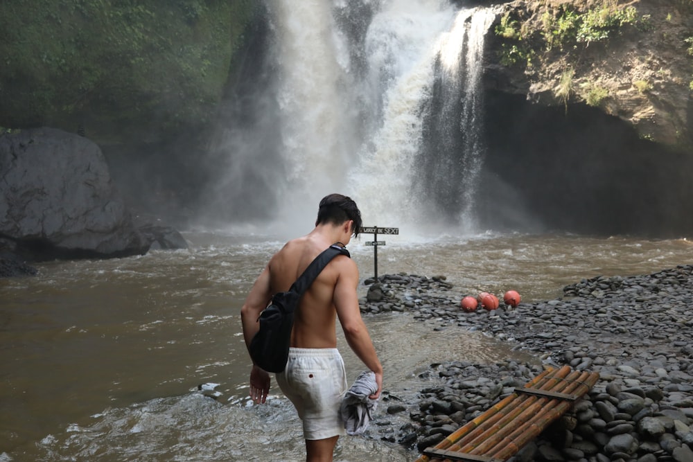 a man walking in front of a waterfall