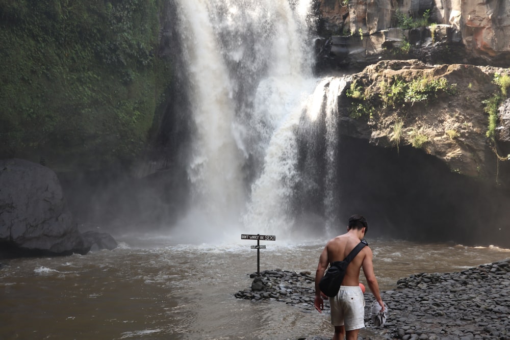 a man standing next to a waterfall