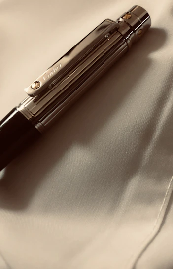 Sleek metallic pens and badges with precise laser-engraved logos displayed on a wooden table.