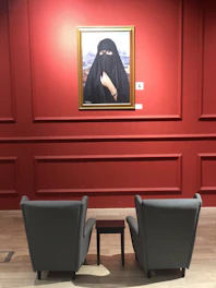 A thoughtful portrait of Nada Emam in a dark, elegant setting with soft beige and gold highlights.