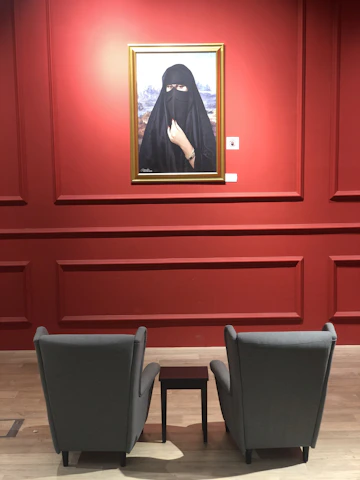 A thoughtful portrait of Nada Emam in a dark, elegant setting with soft beige and gold highlights.