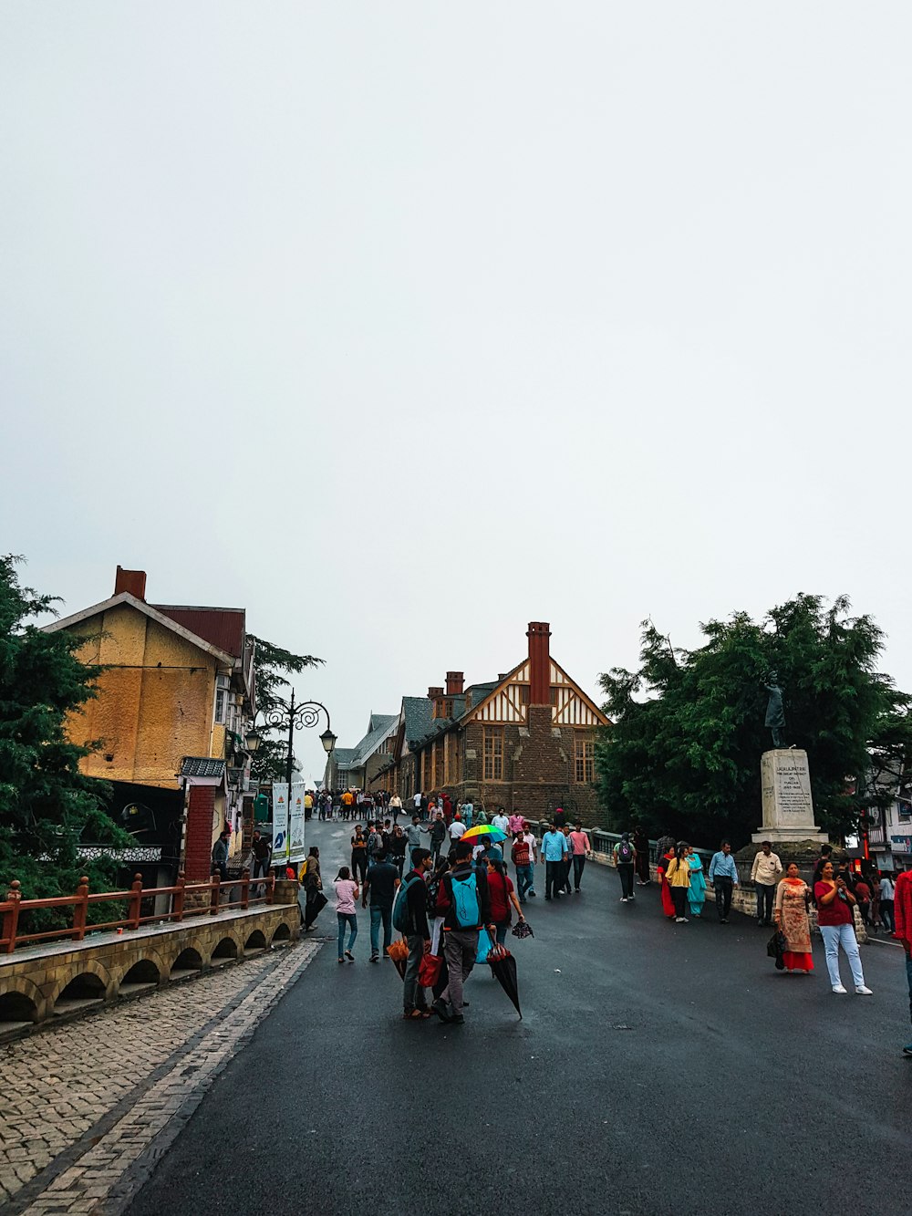 a group of people walking on a road with buildings on either side