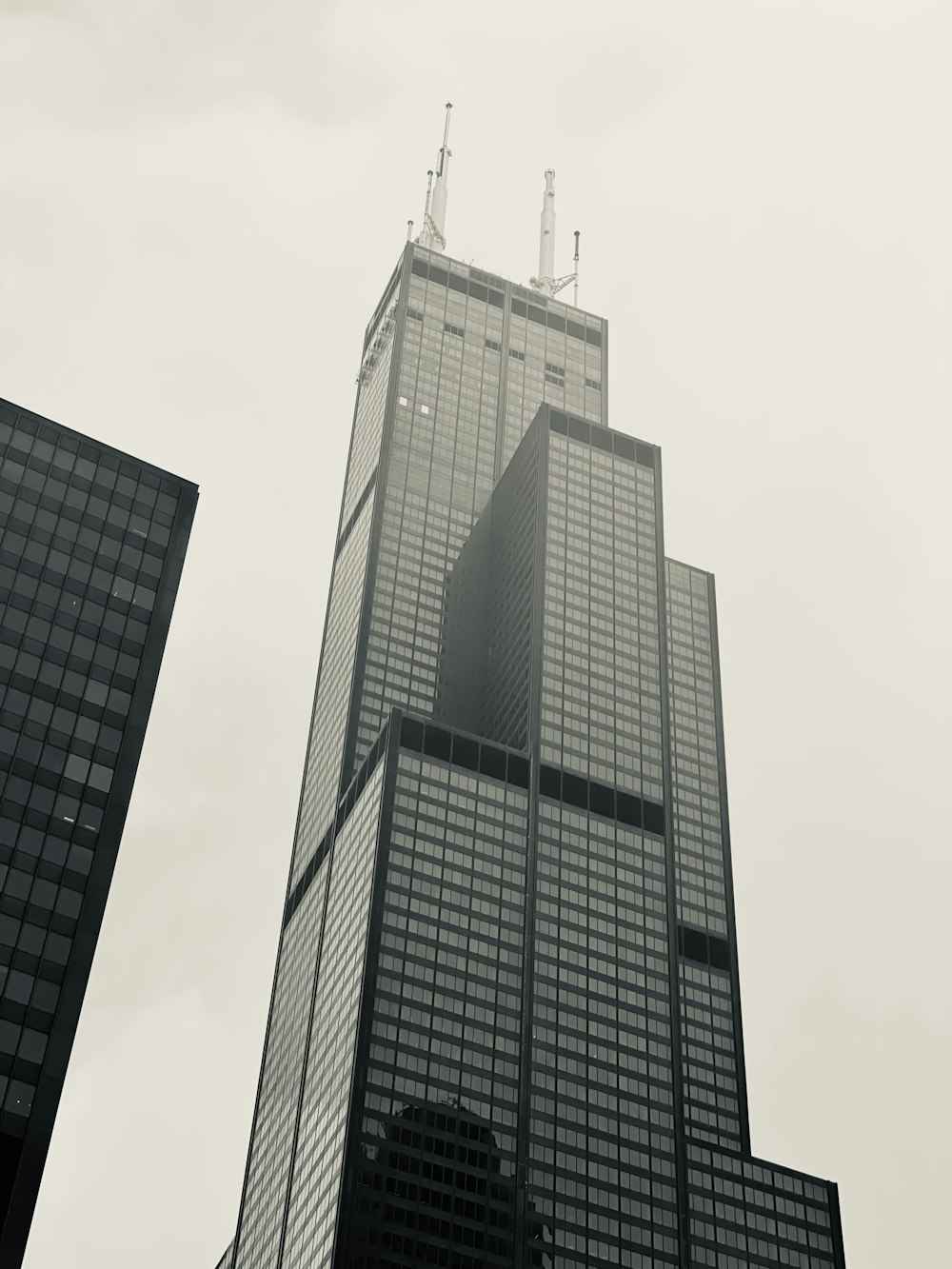 a tall building with a pointy top with Willis Tower in the background