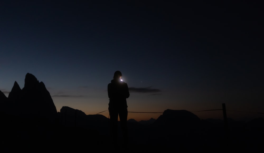 una persona in piedi di fronte a un tramonto