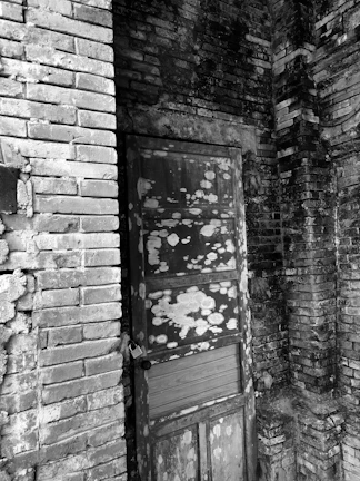 A door that does not fit properly in an old building doorway with uneven walls.