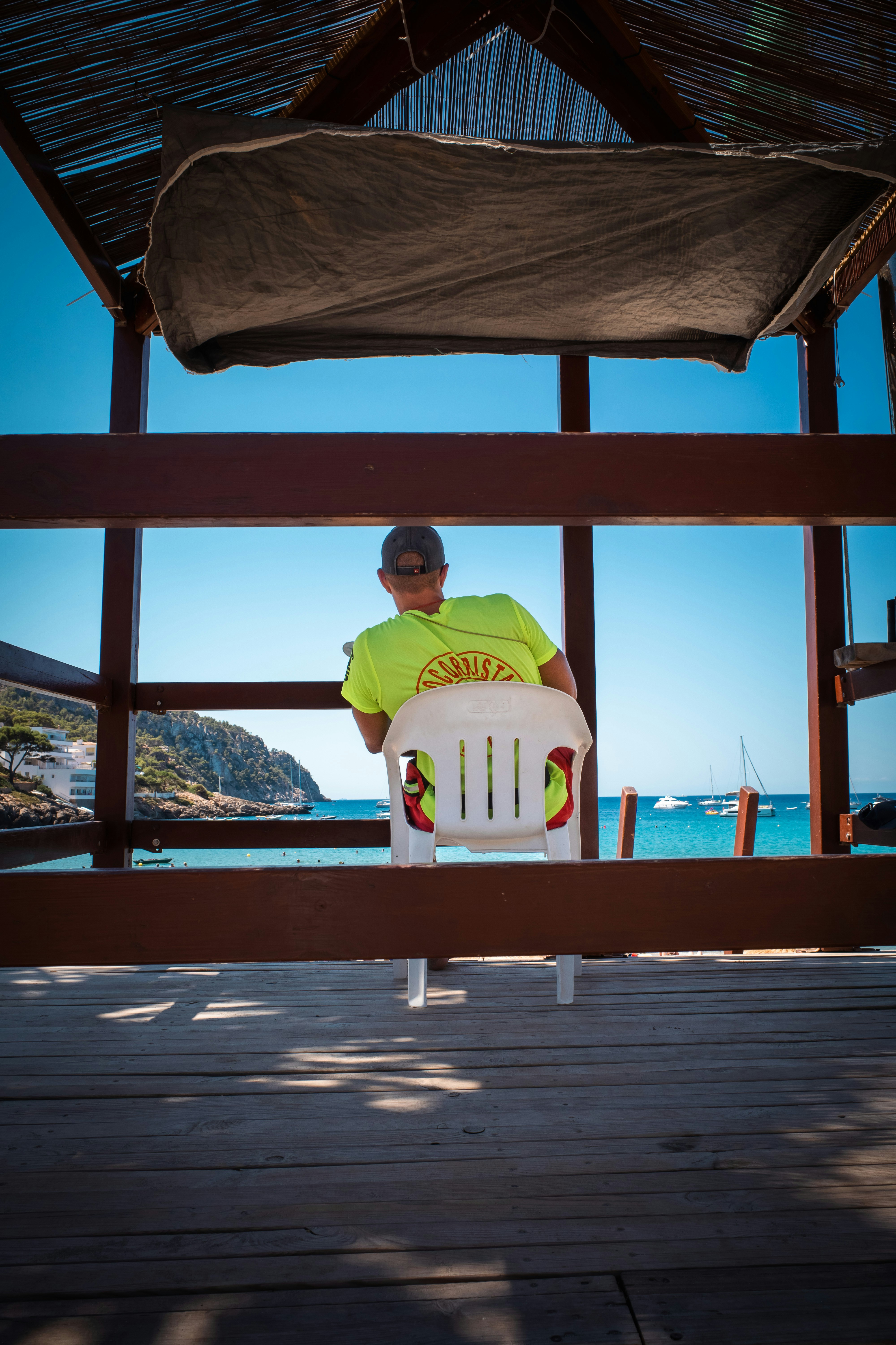 Lifeguard sits on chair overlooking the ocean