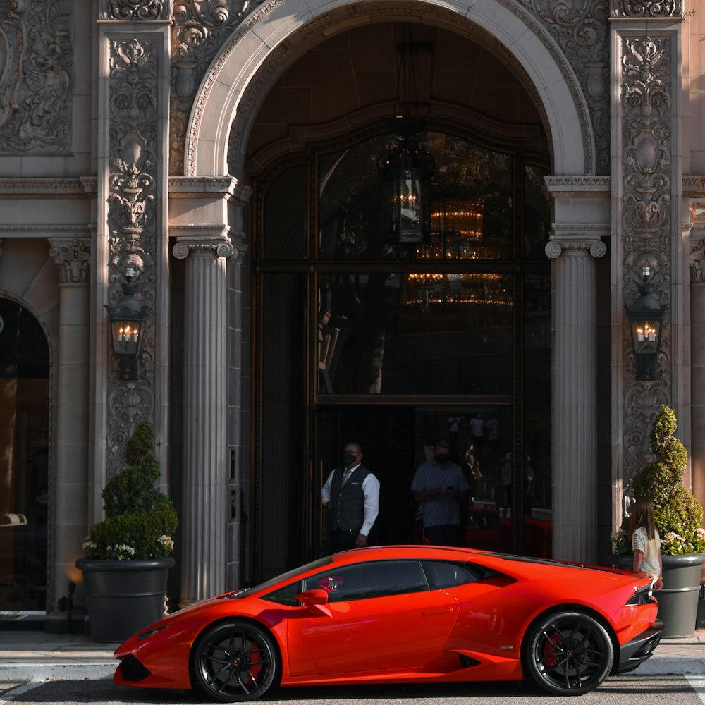 a red sports car parked in front of a building with columns