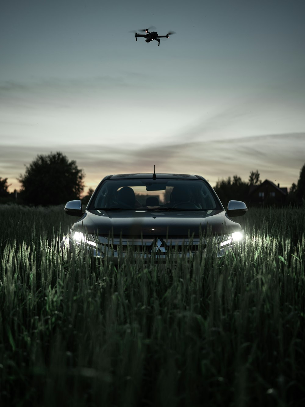 a car parked in a field with a helicopter flying in the sky