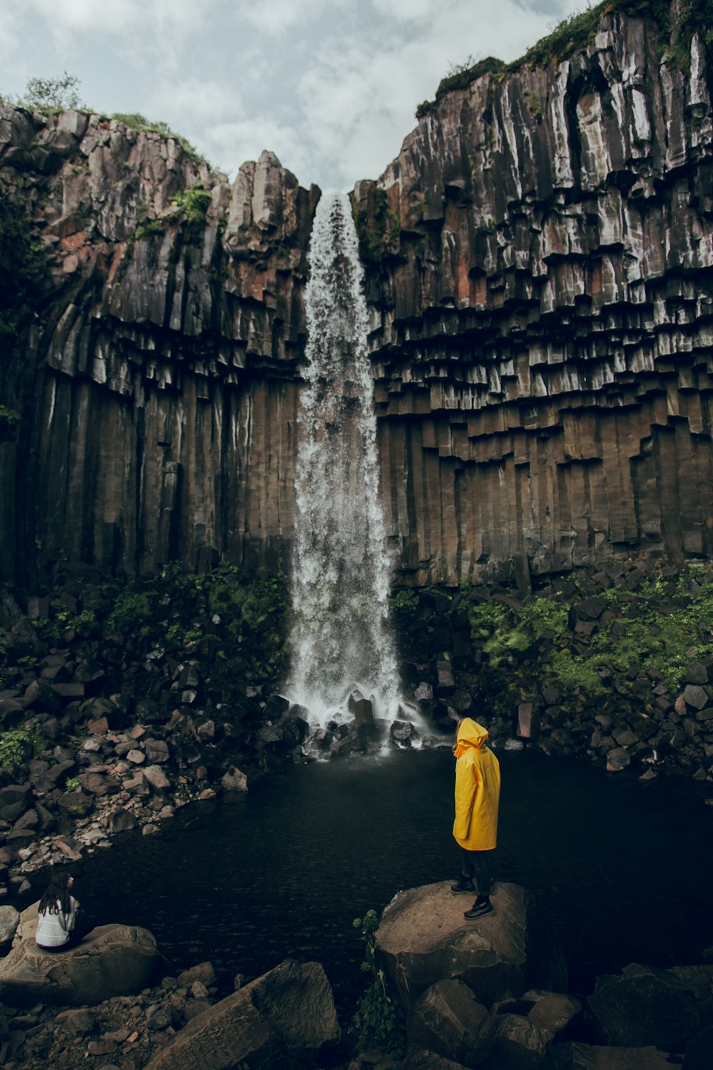 a person standing on a rock near a waterfall