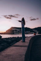 a person standing on a stone wall looking at a body of water