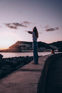a person standing on a stone wall looking at a body of water
