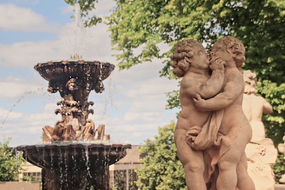 a statue of a man and a woman in front of a fountain