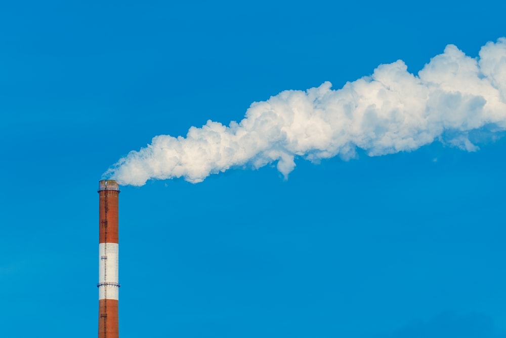 a smokestack with a cloud of smoke in the sky