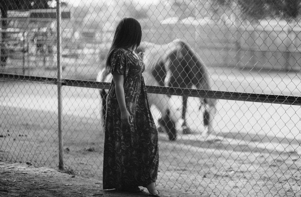 une personne debout devant une clôture regardant un chien