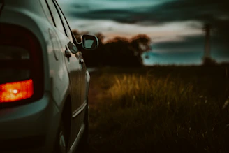 Tow truck pulling a car on a quiet roadside at dusk.