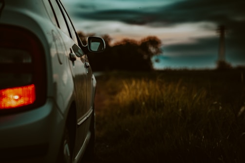 A taxi parked by a rural roadside at sunset.