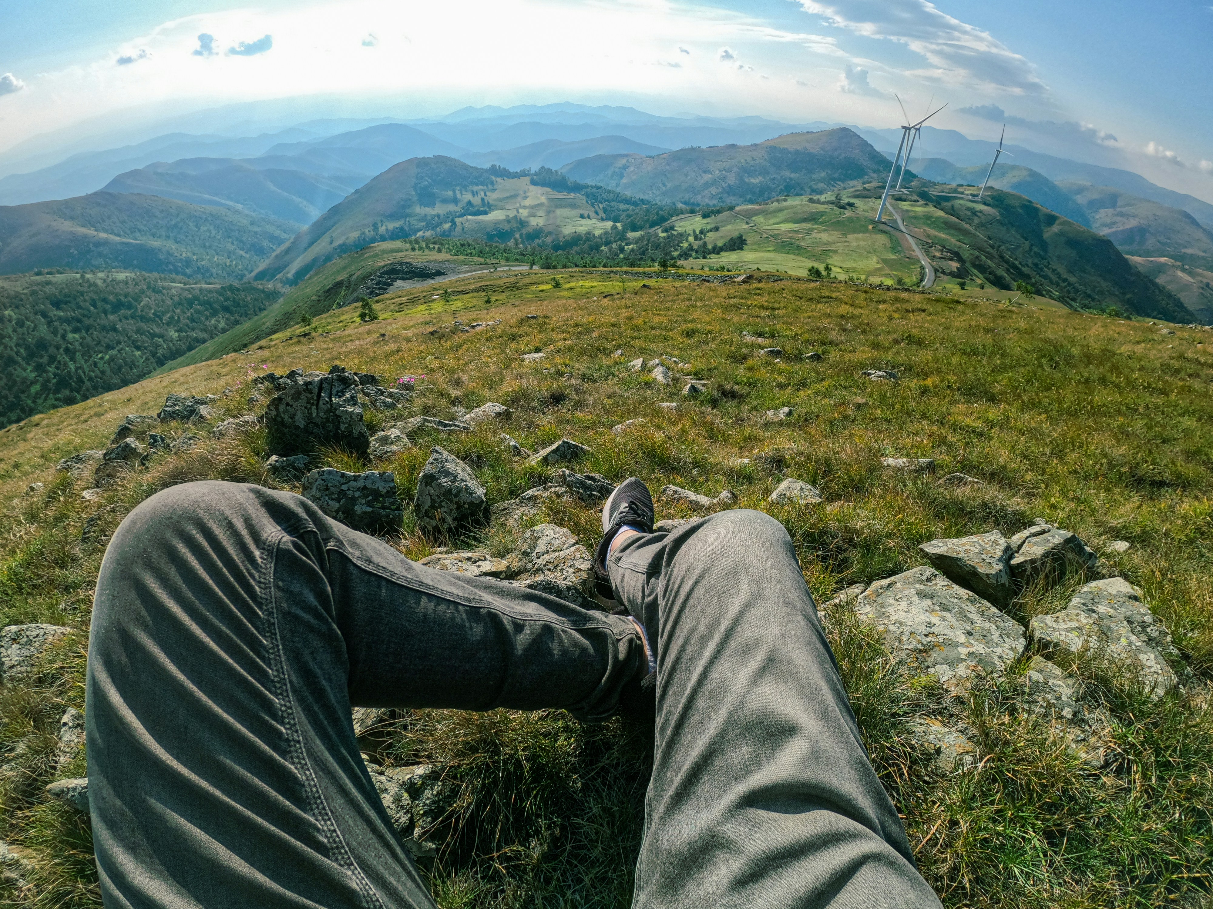 Die Beine einer Person auf einem Felsen mit Blick auf ein Tal