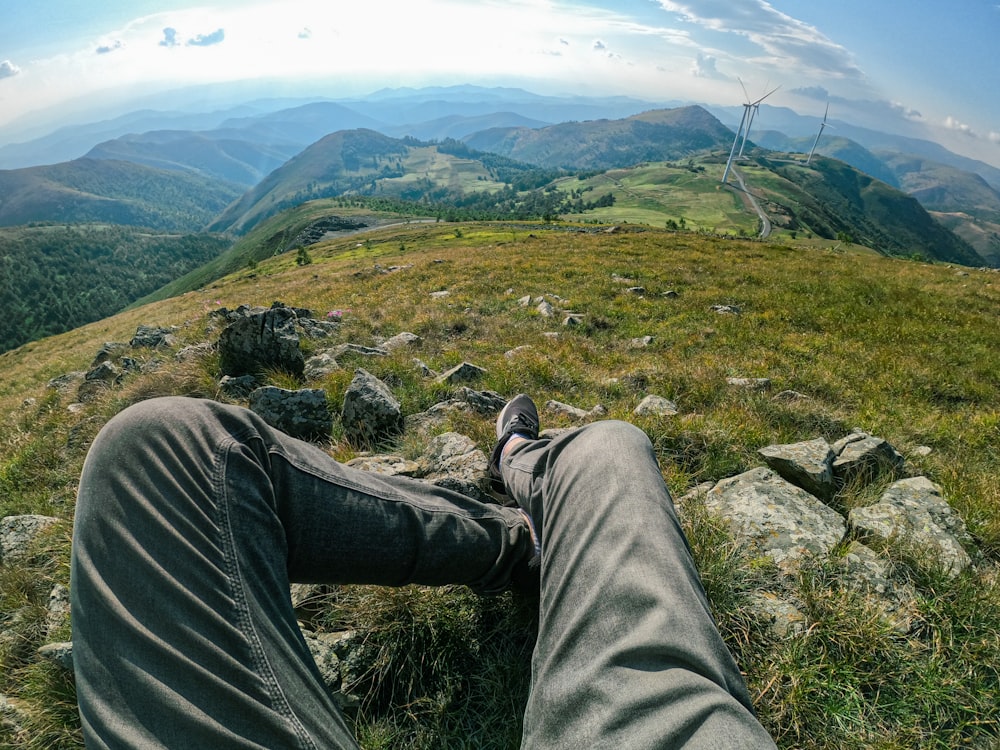 a person's legs on a rock overlooking a valley