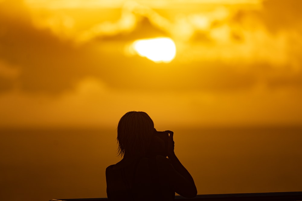 a person taking a picture of the sun