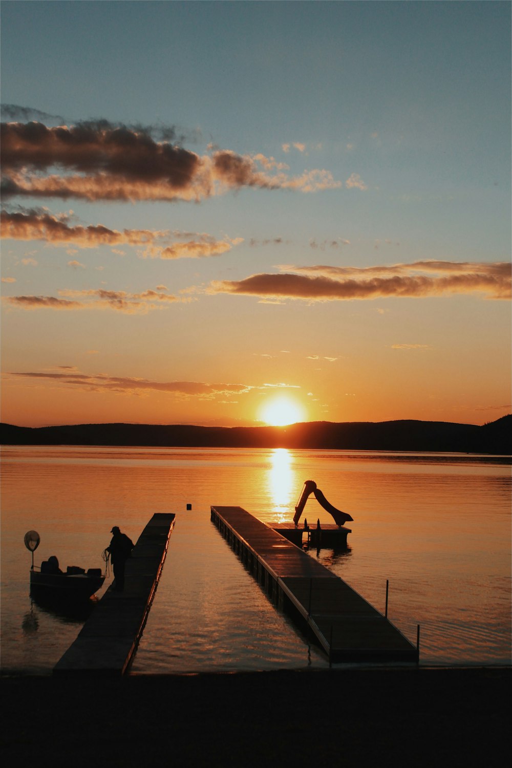 a person sitting on a dock looking at the sunset