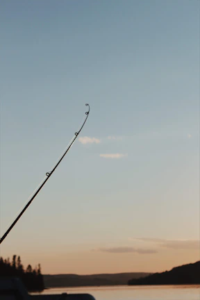 Close-up of a fishing rod casting into a calm northern Ontario lake at sunset