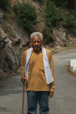 A supportive caregiver helping an older man walk steadily using a walker outdoors